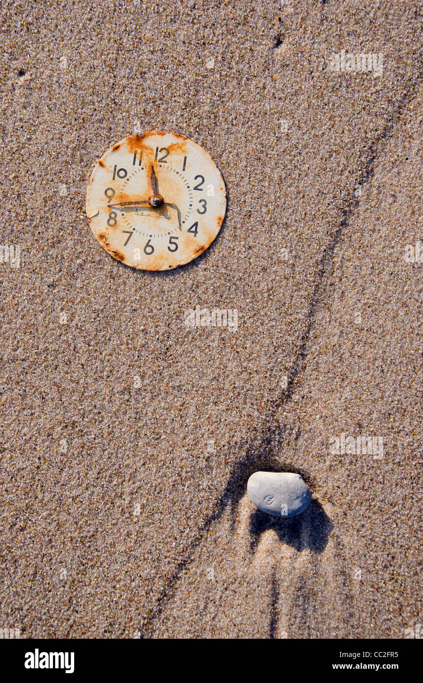 verrostete Zifferblatt und Stein auf dem Meer Strandsand Stockfoto
