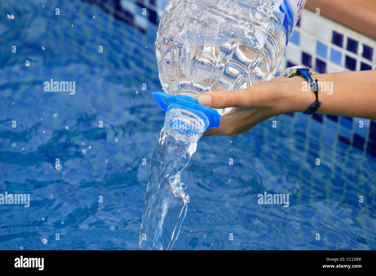 Ausgießen von Wasser in Flaschen in einen pool Stockfoto