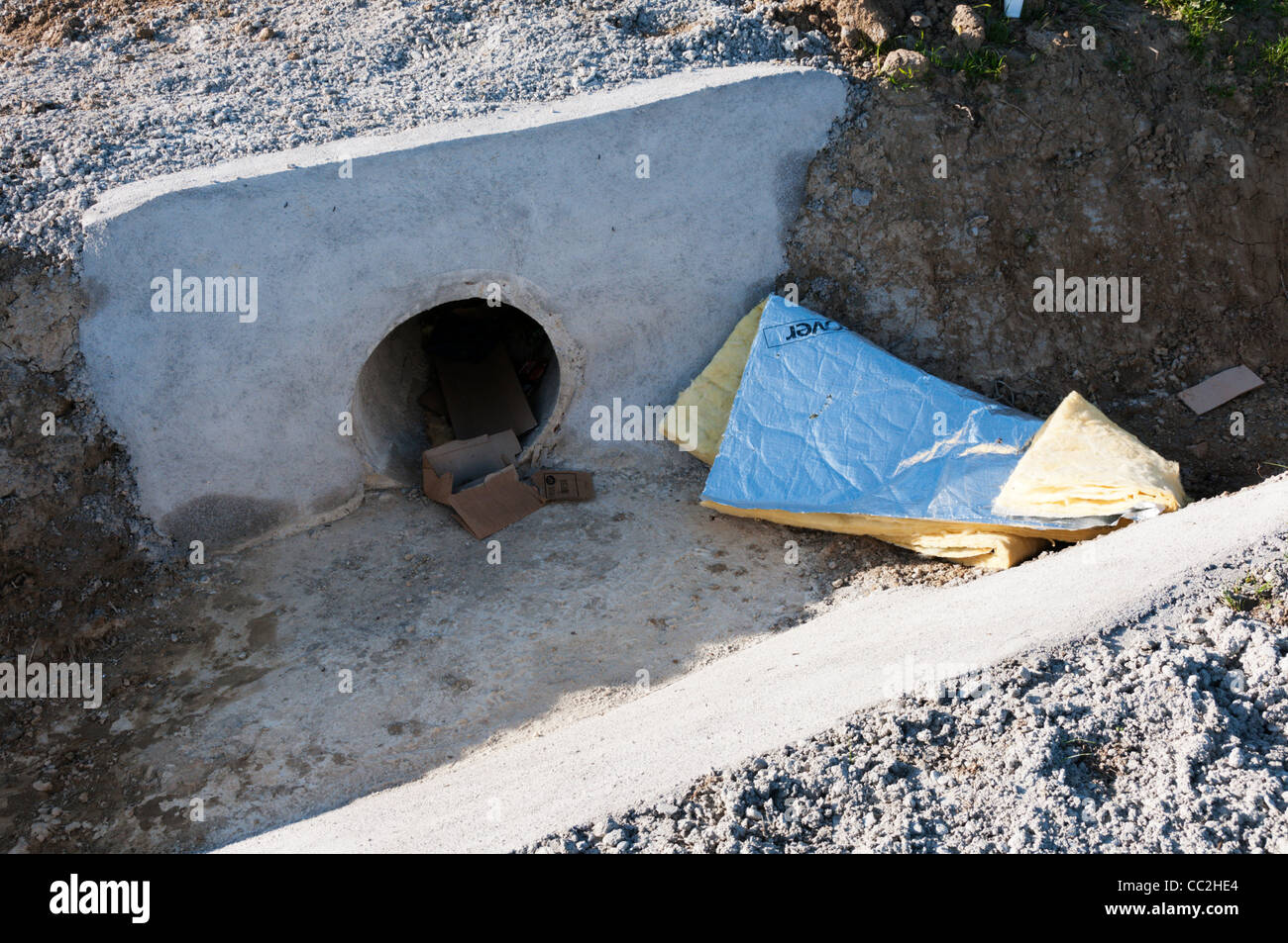 Builders Müll in einem konkreten Abfluss oder Düker am Rande einer Baustelle. Stockfoto