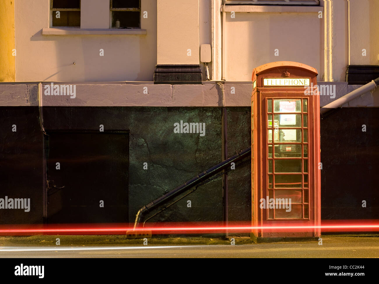 Nacht Schuss von UK Phonebox mit Lichtspuren von vorbeifahrenden Autos. Stockfoto