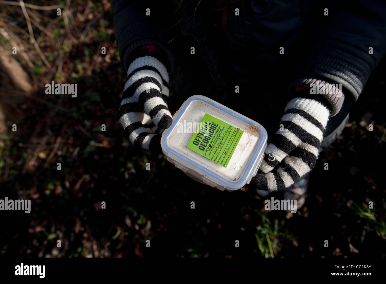 Kind mit gestreiften Handschuhen halten Geocache-box Stockfoto