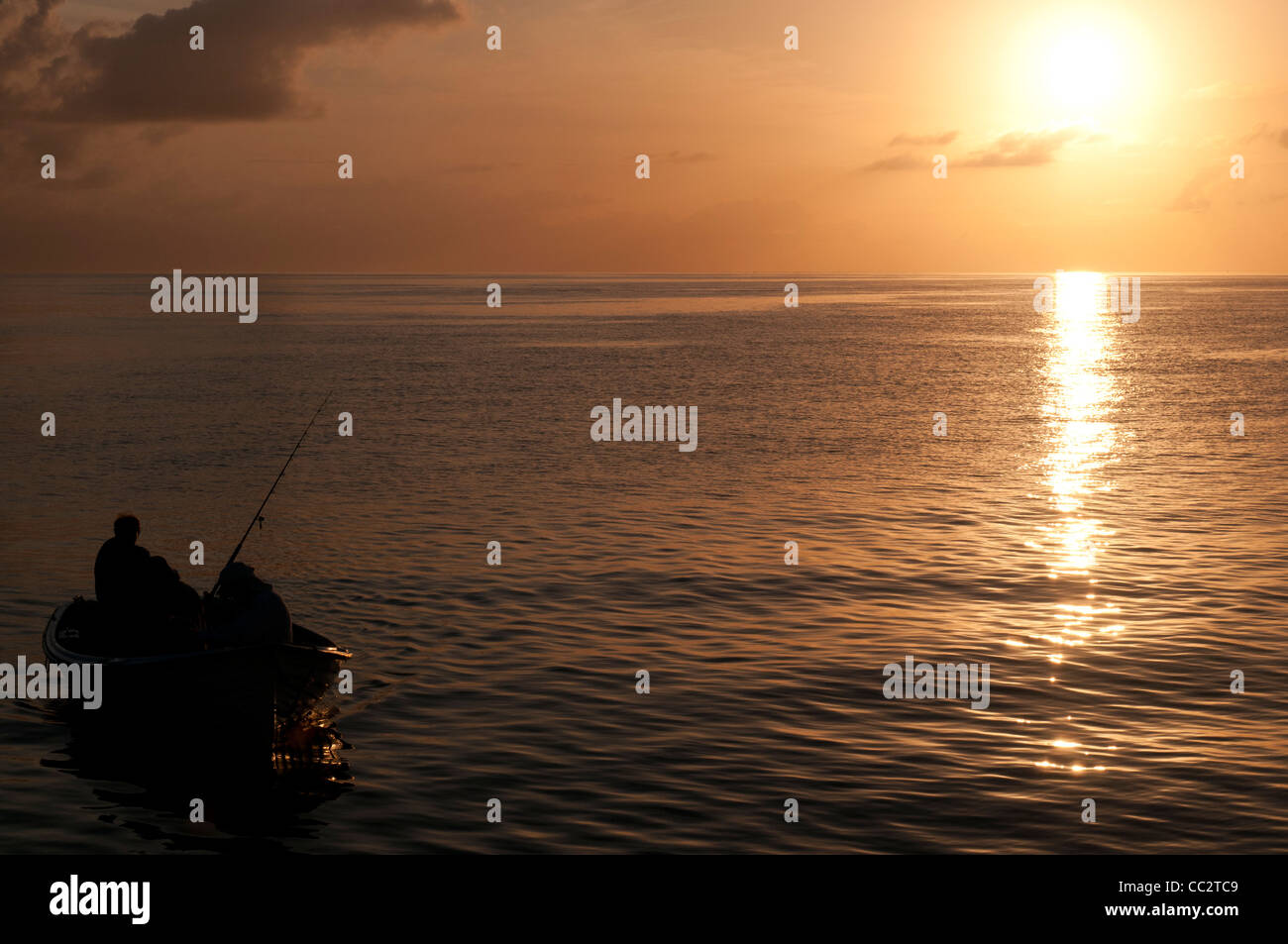 Fischer in Boat Silhouette Great Barrier Reef Queensland Australien // Ein kleines Boot mit Fischer kommt am Ende des Tages an einem ruhigen Tag am Great Barrier Reef, Queensland, Australien, vor der untergehenden Sonne. Stockfoto