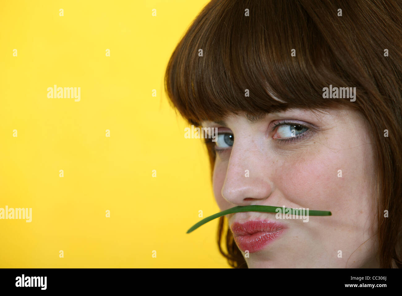 Frau hält eine grüne Bohnen zwischen ihre Lippen und Nase Stockfoto