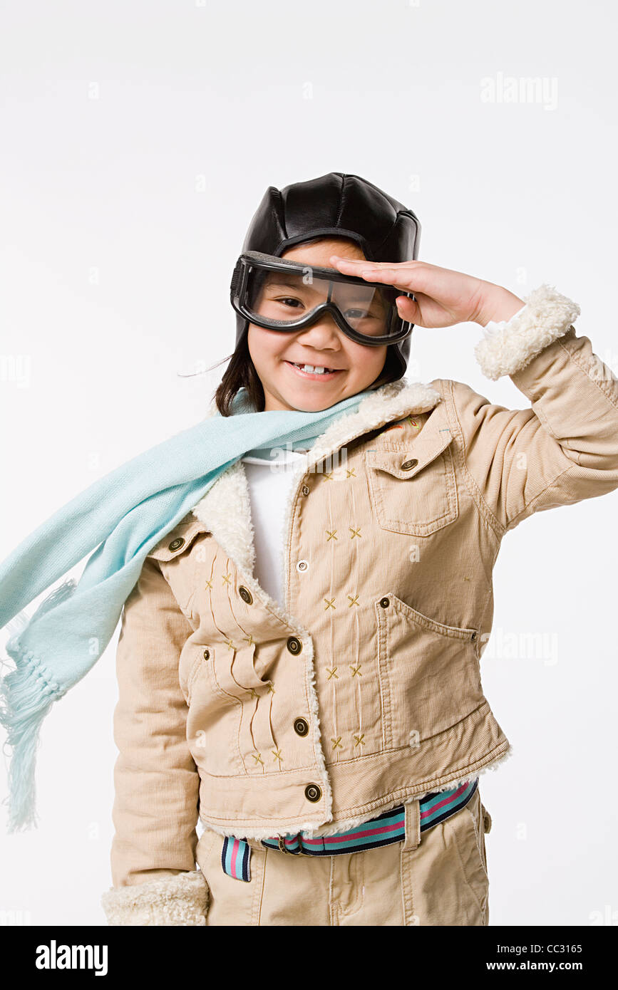Studioportrait von salutieren Mädchen (8-9) trägt Flieger Mütze und Brille fliegen Stockfoto