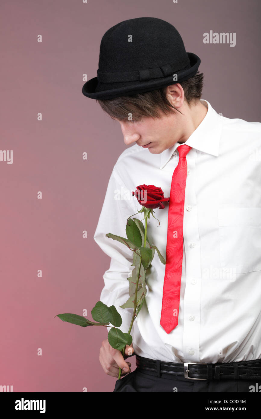 Junge Männer mit der roten Rose auf Farbe Hintergrund. Liebe und Reflexion. Stockfoto