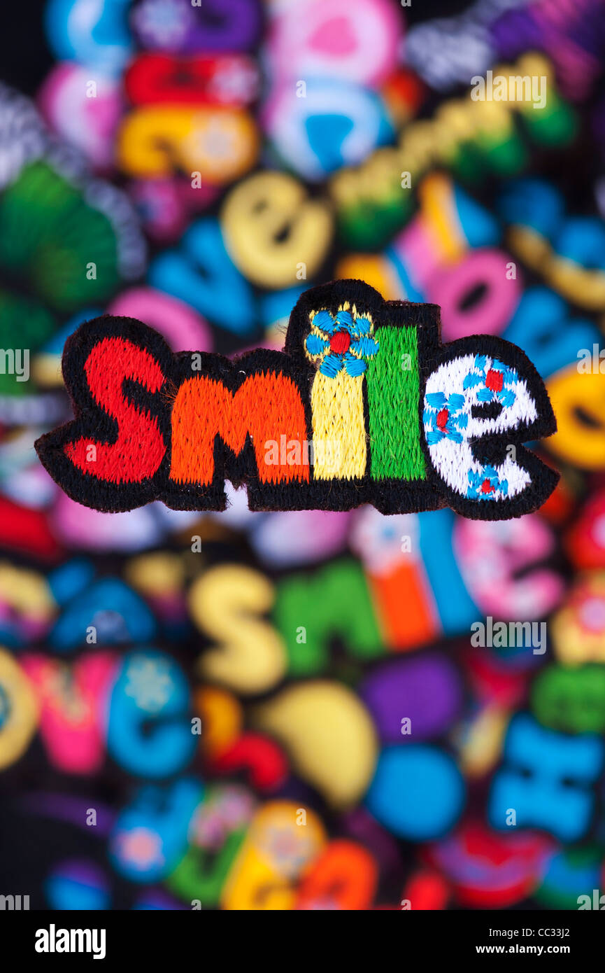 Stickerei-Eisen auf Flecken von bunten Lächeln, Liebe, Frieden, Happy und Groovy Worte auf einem schwarzen Hintergrund Stockfoto