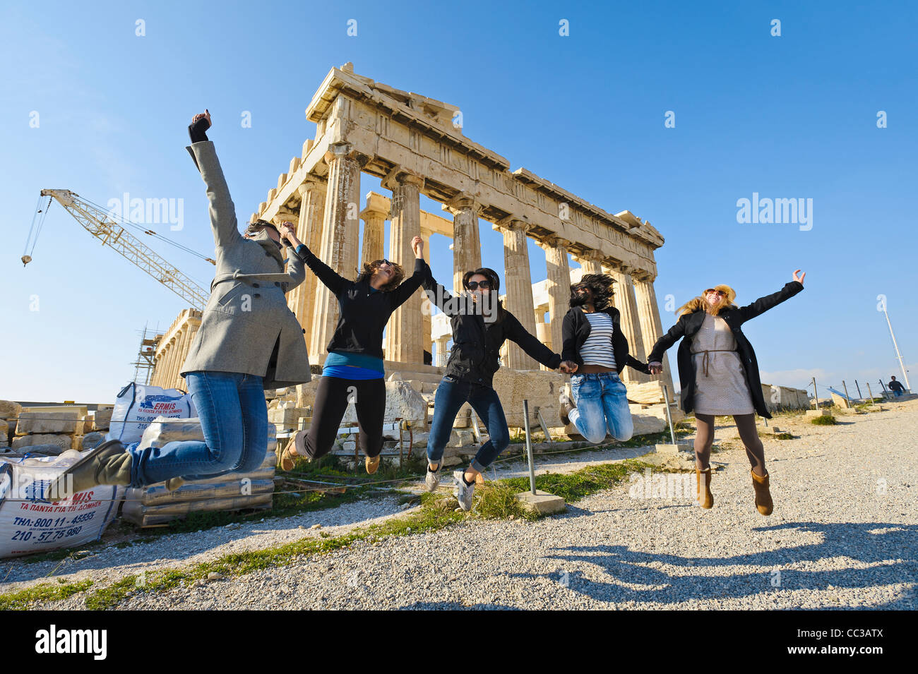 Junge Frauen springen vor dem Parthenon Tempel, Akropolis, Athen, Griechenland, Europa Stockfoto