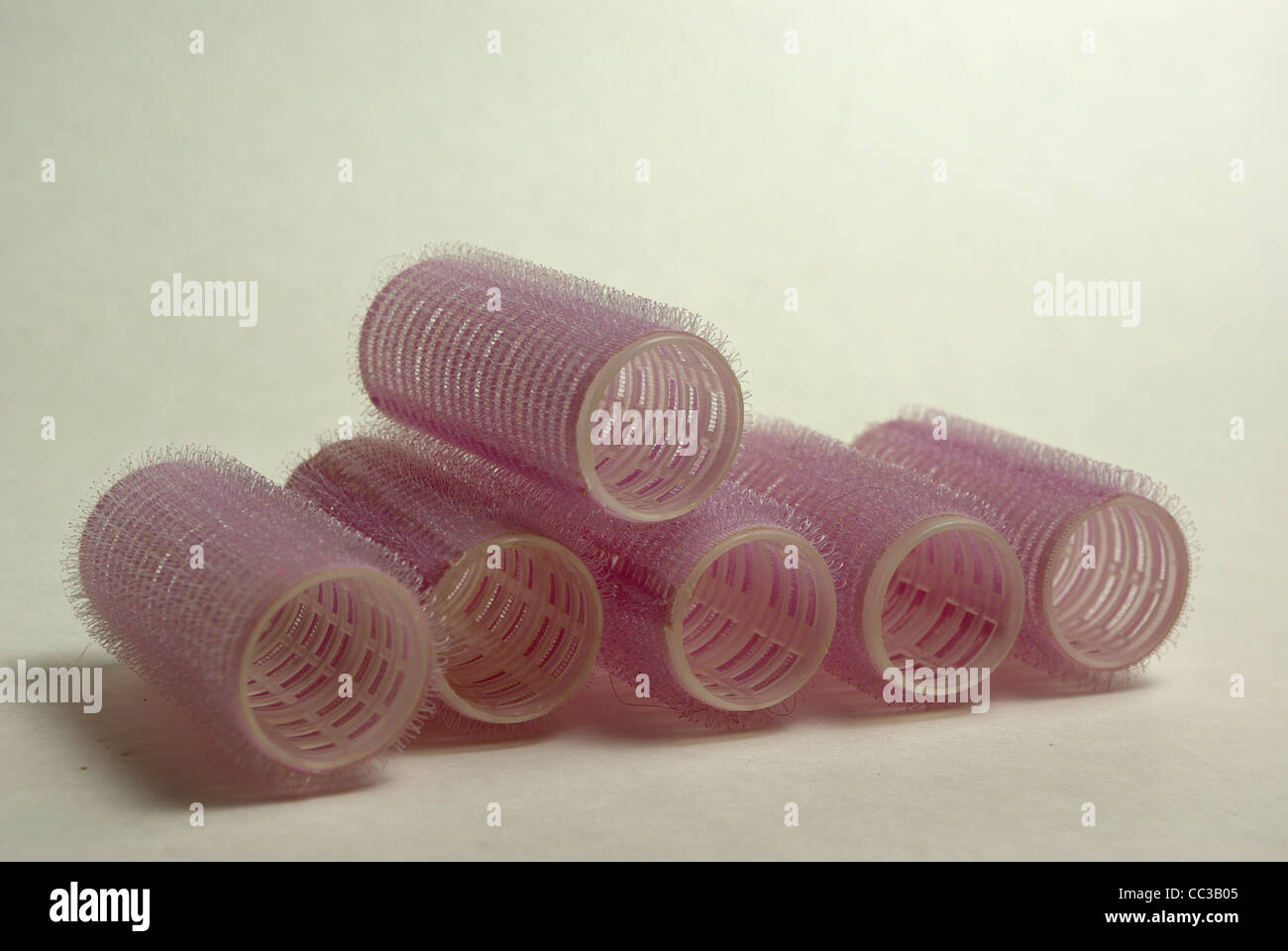 Rosa Lockenwickler sitzen auf einem einfarbigen Hintergrund Stockfoto