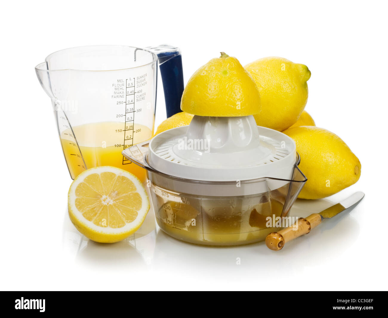 Zitronenpresse mit Saft, frische Zitronen, Messer und Mess Krug Stockfoto