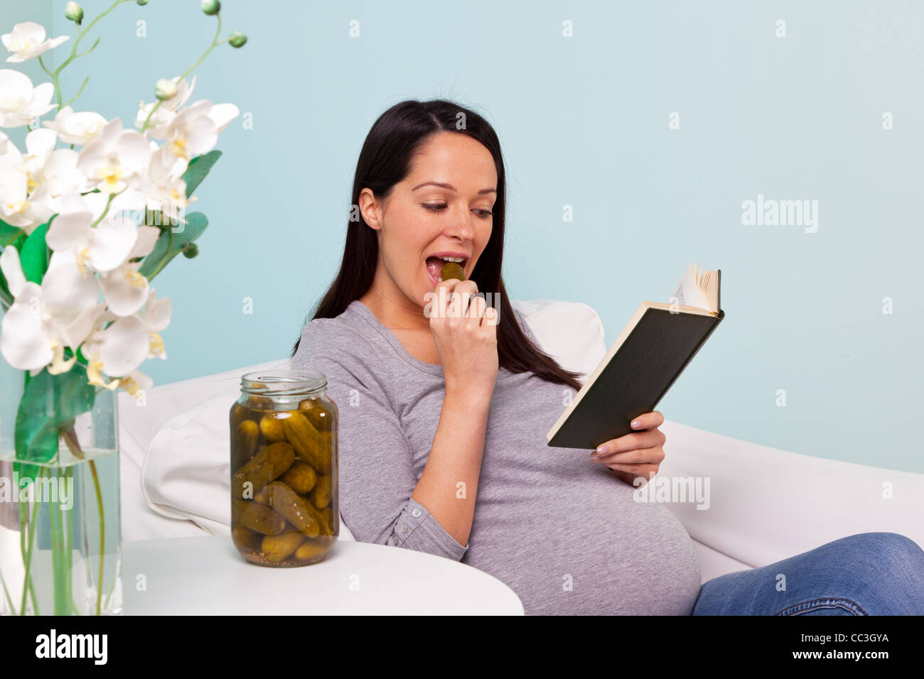 Foto von einer schwangeren Frau zu Hause sitzt in einem Sessel mit einem verlangen nach Essiggurken. Stockfoto