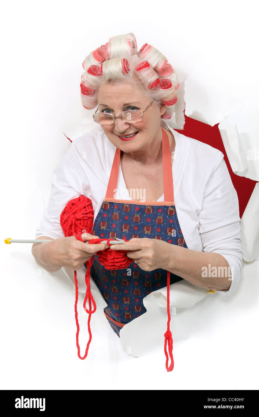 Ältere Frau mit Lockenwickler, während stricken Stockfoto