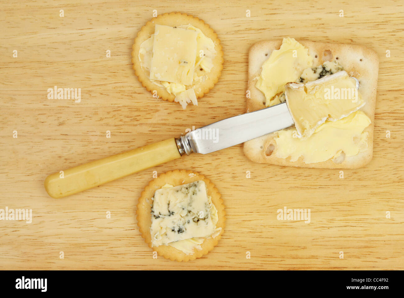 Gebäck, Käse und Butter Messer auf einem Holzbrett Stockfoto