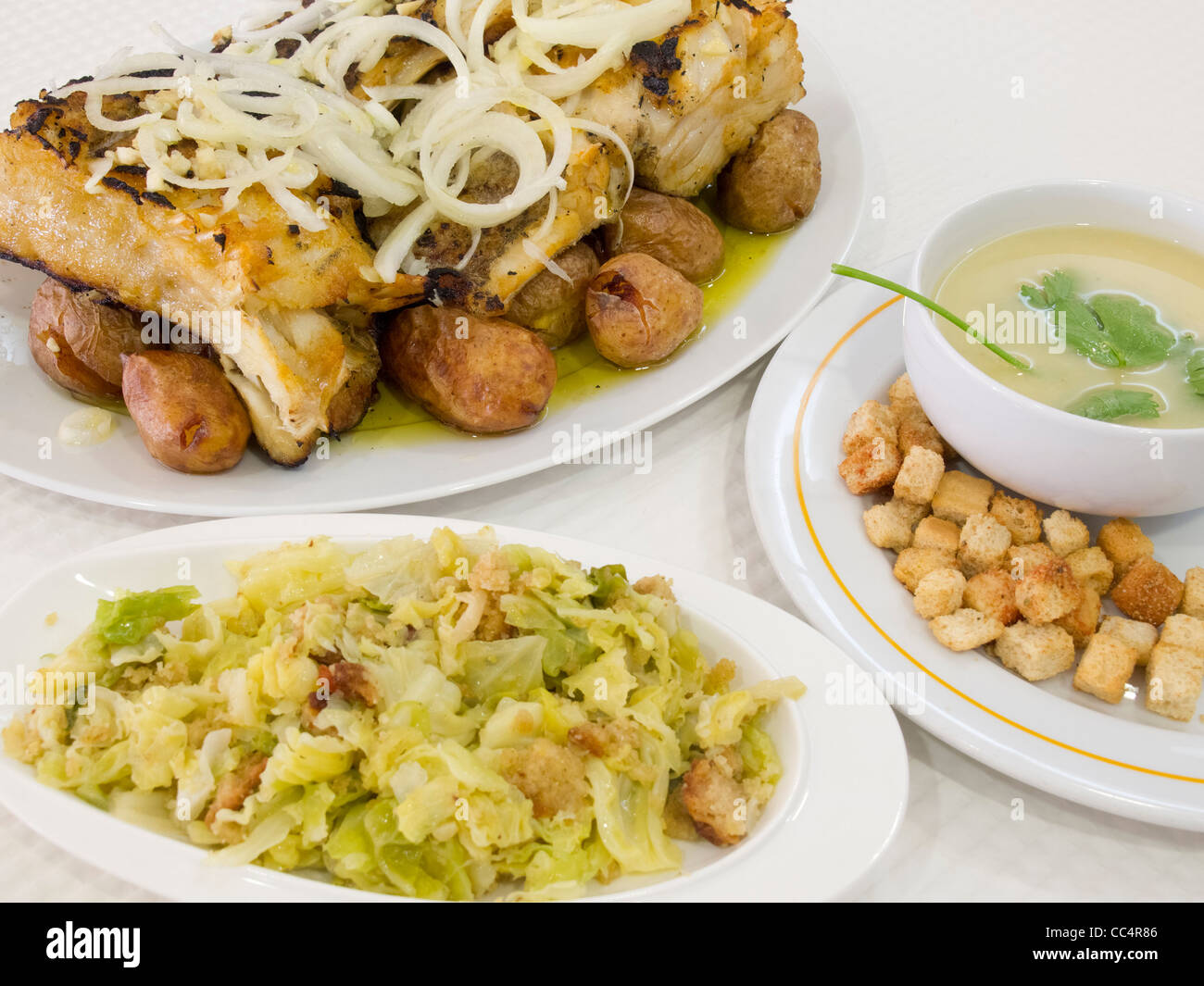 Typische portugiesische Gerichte 'Bacalhau À Lagareiro' (Kabeljau), "Migas" und Suppe mit Brot Croutons Stockfoto