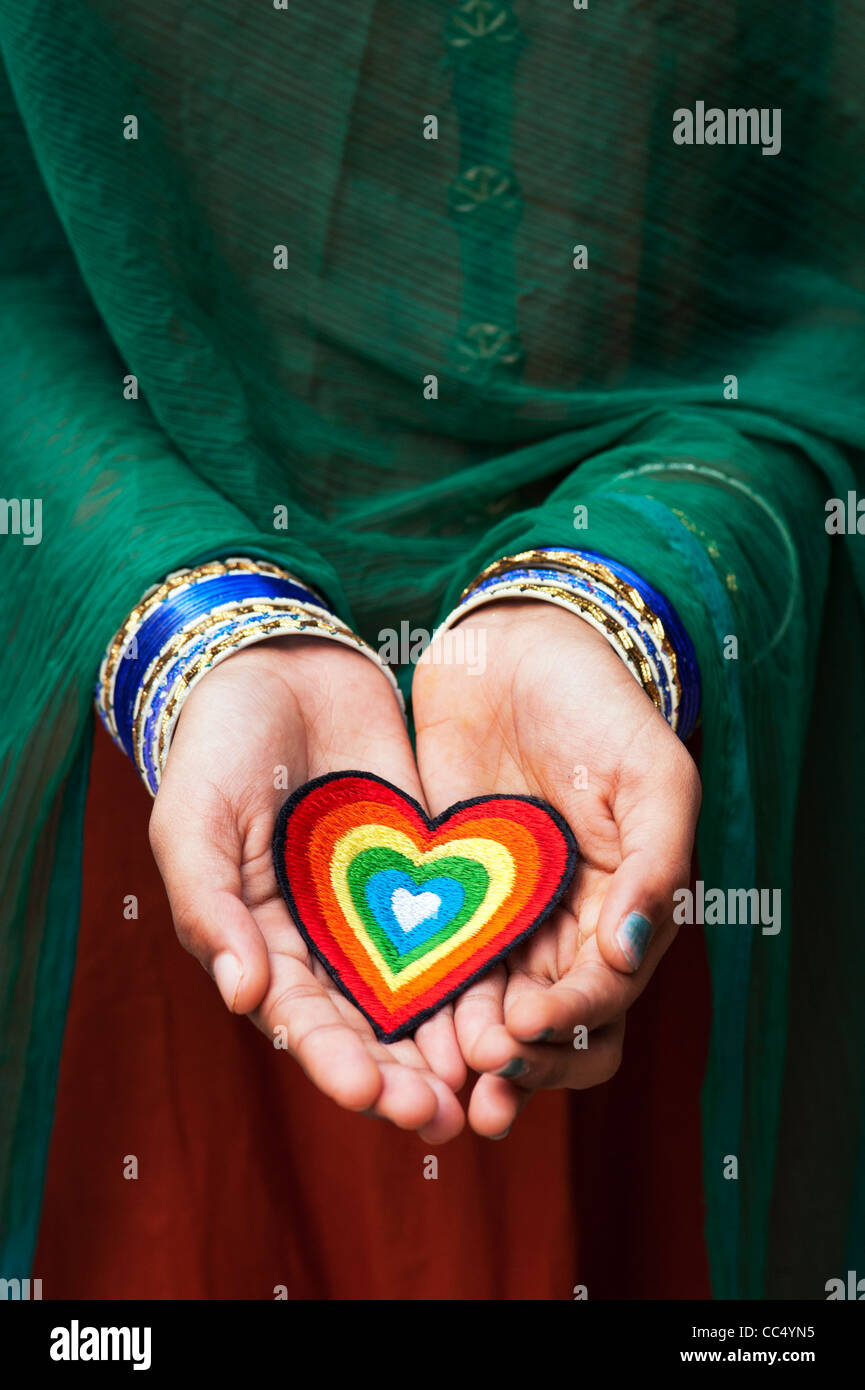 Indische Mädchen Hände halten eine Stickerei Bügeleisen auf Patch von einem bunten Liebe Herz. Indien Stockfoto