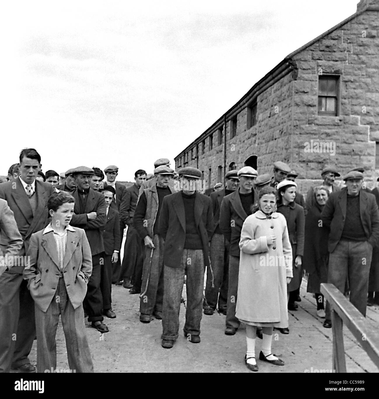 Aran Inselbewohner zusehen, wie Besucher auf Kilronan Pier Inish mehr 1955 an Land kommen Stockfoto