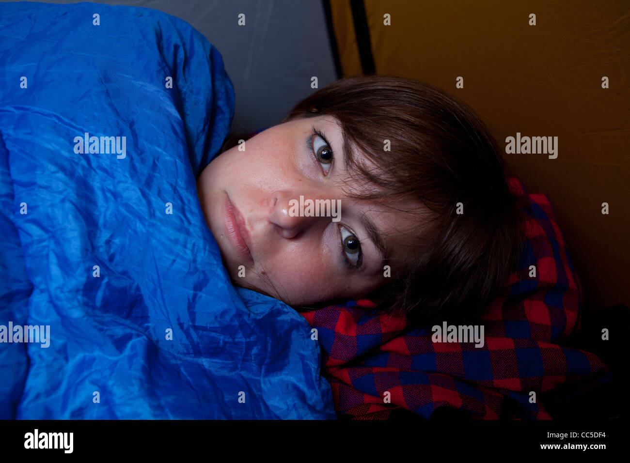 Eine junge Frau eingehüllt in einen Schlafsack beim camping in Cornwall. Stockfoto