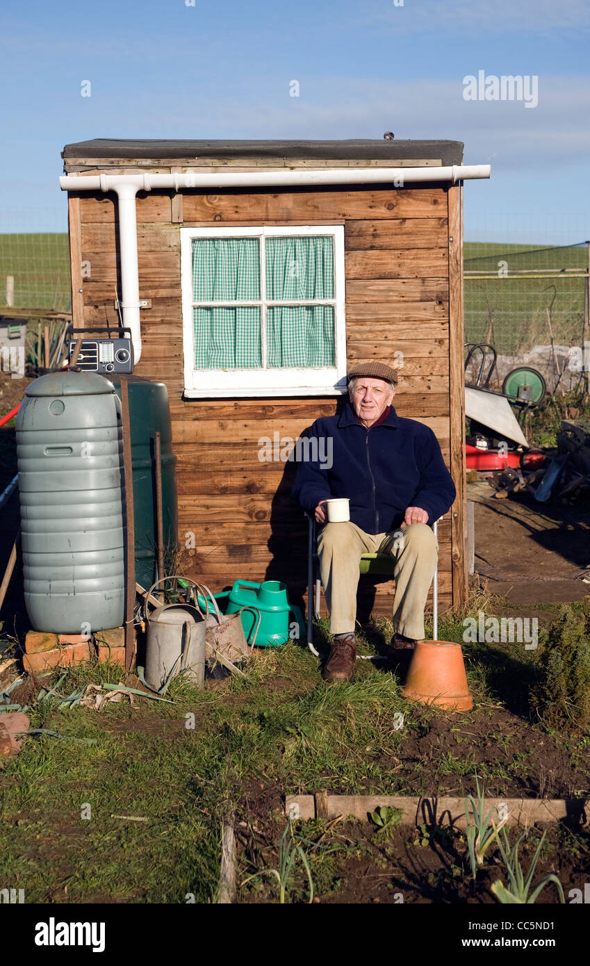 Ältere Mann sitzt durch Schuppen Schrebergarten Stockfoto