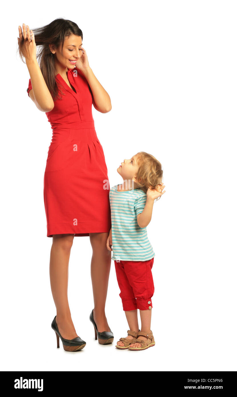 Kleines Mädchen steht mit einer Frau im roten Kleid und berührende Haare Stockfoto