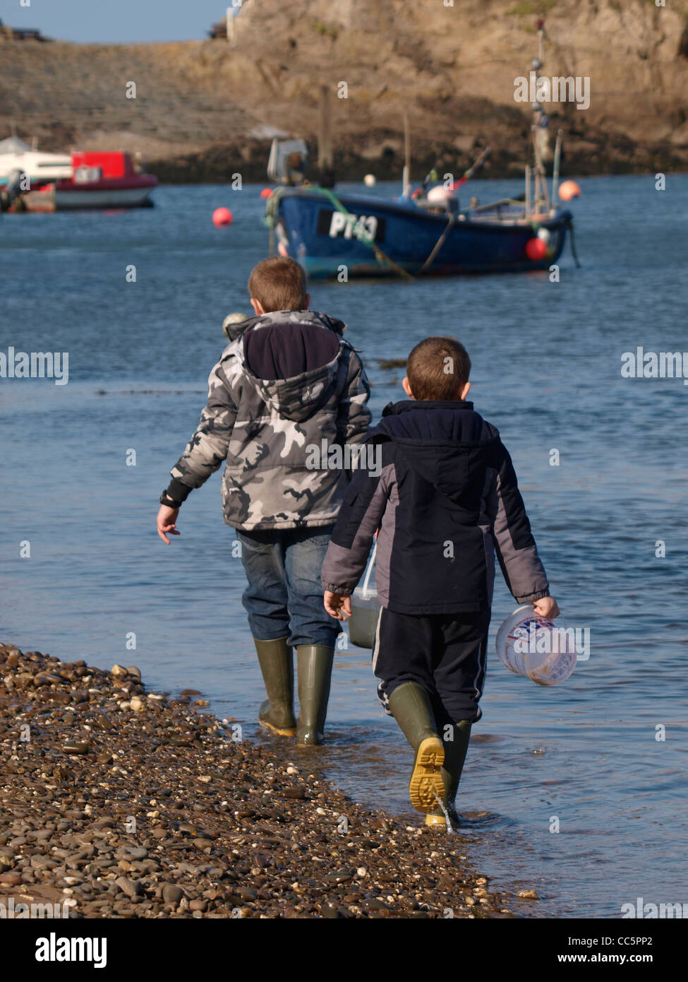 Zwei jungen, die zu Fuß entlang des Wassers Rand, Bude, Cornwall, UK Stockfoto
