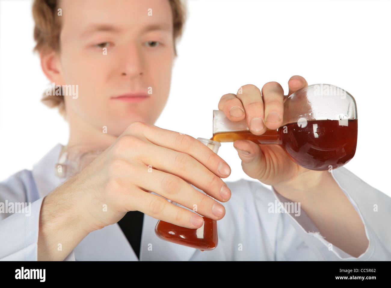 Chemiker gießt braune Flüssigkeit aus einer Flasche in einem anderen Stockfoto