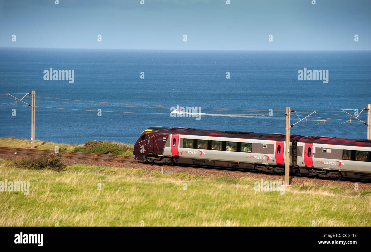 Personenzug auf der East Coast Mainline nahe der schottischen Grenze zu Nordsee im Hintergrund. Stockfoto