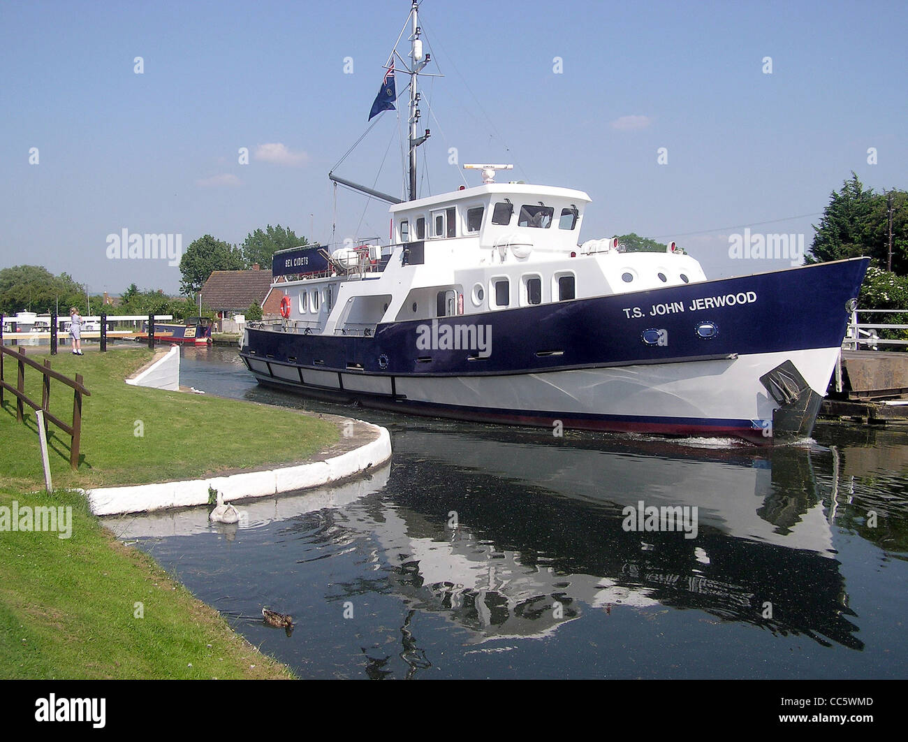 Das Sea Cadet-Ausbildungsschiff T.S. John Jerwood befährt die Patch Bridge auf dem Gloucester & Sharpness Canal auf dem Weg zum Fluss Severn. Der Kanal befindet sich in der Nähe von Slimbridge, Gloucestershire, bekannt für seine Feuchtgebiete und Wildfowl Reserve. Stockfoto