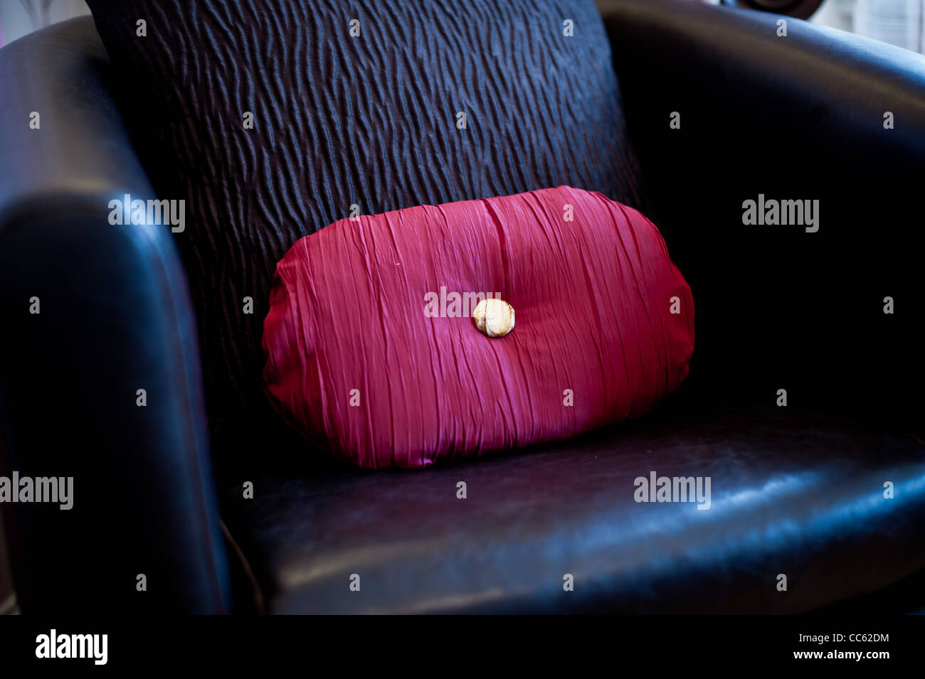 Leuchtend rote Kissen in einem Leder-Sessel Stockfoto