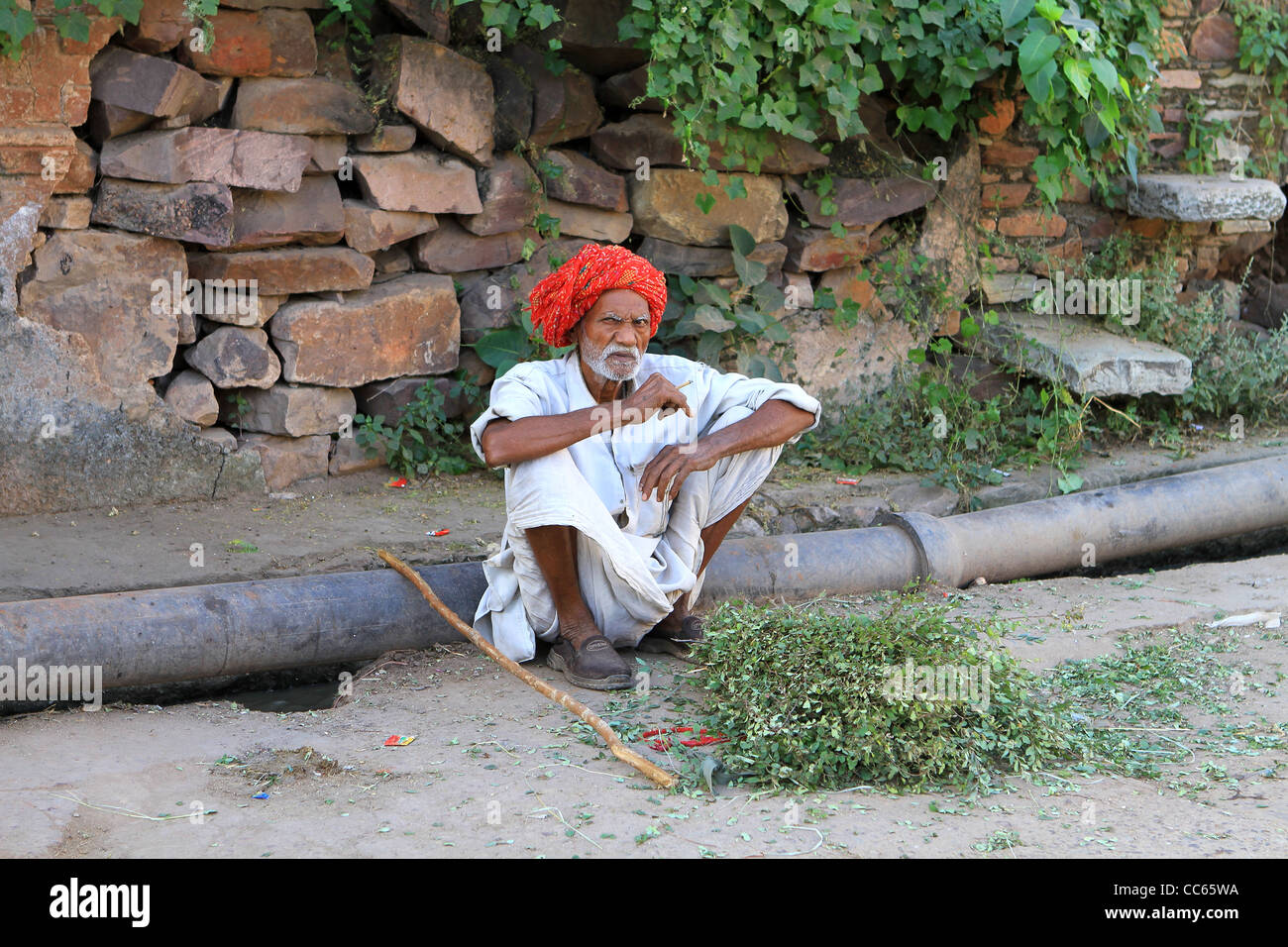 Indischer Mann mit rotem Turban auf einem Rohr sitzen. Bundi. Rajasthan. Indien Stockfoto