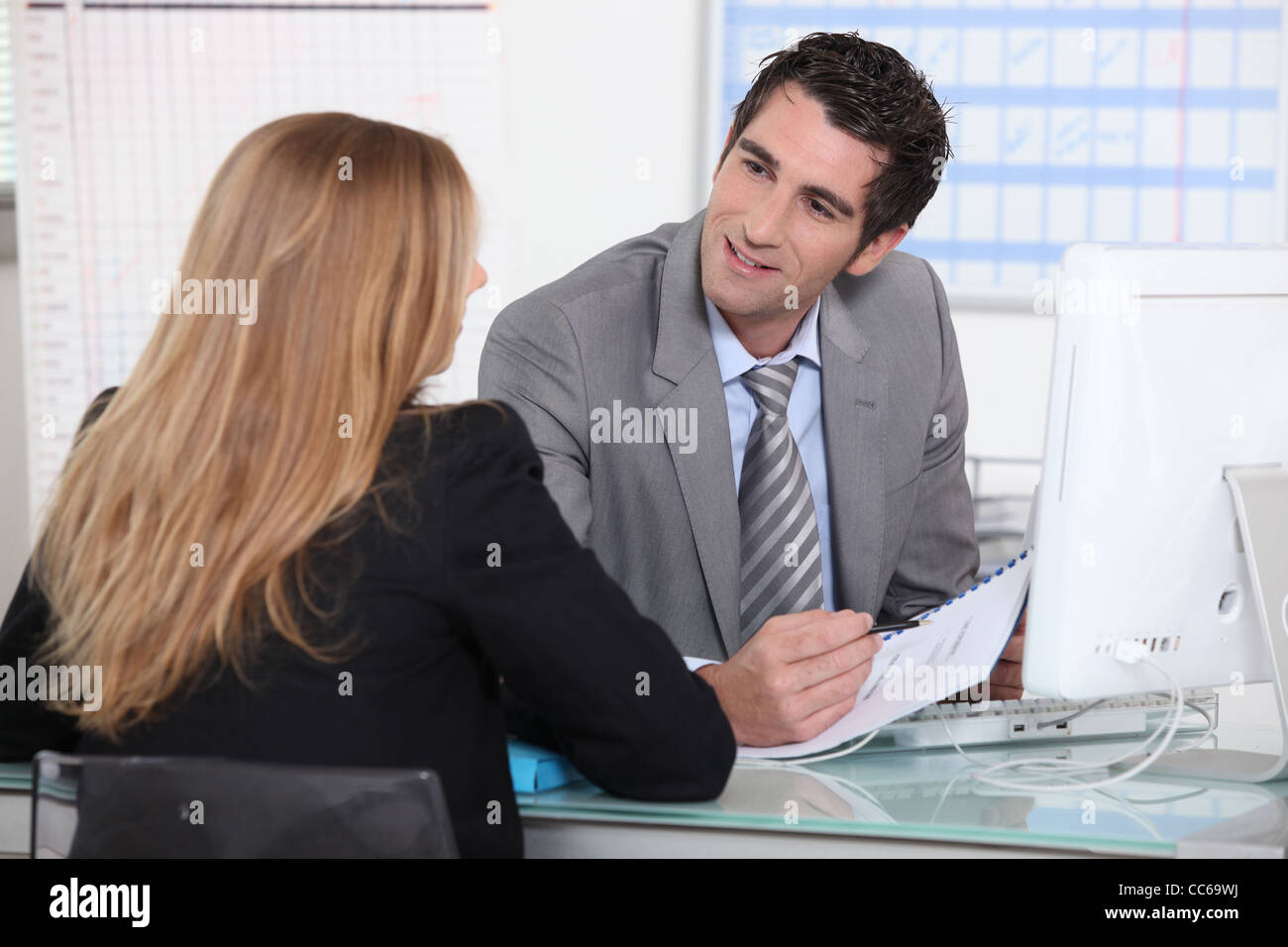 Mann, eine junge Frau auf einem Schreibtisch zu interviewen Stockfoto