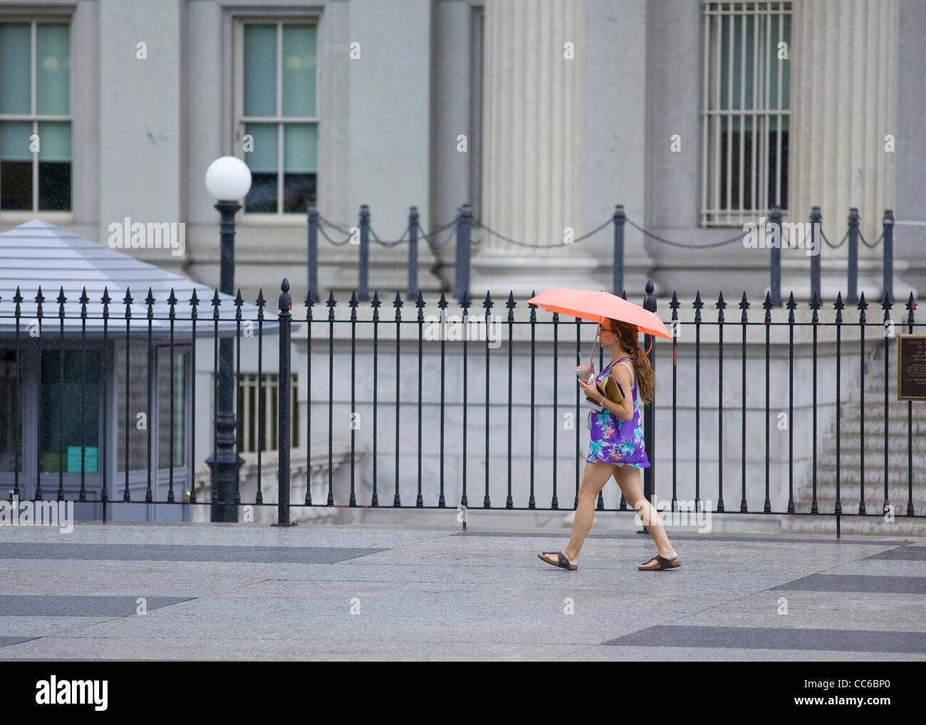 Eine Frau allein zu Fuß an einem regnerischen Tag mit einem Regenschirm - USA Stockfoto