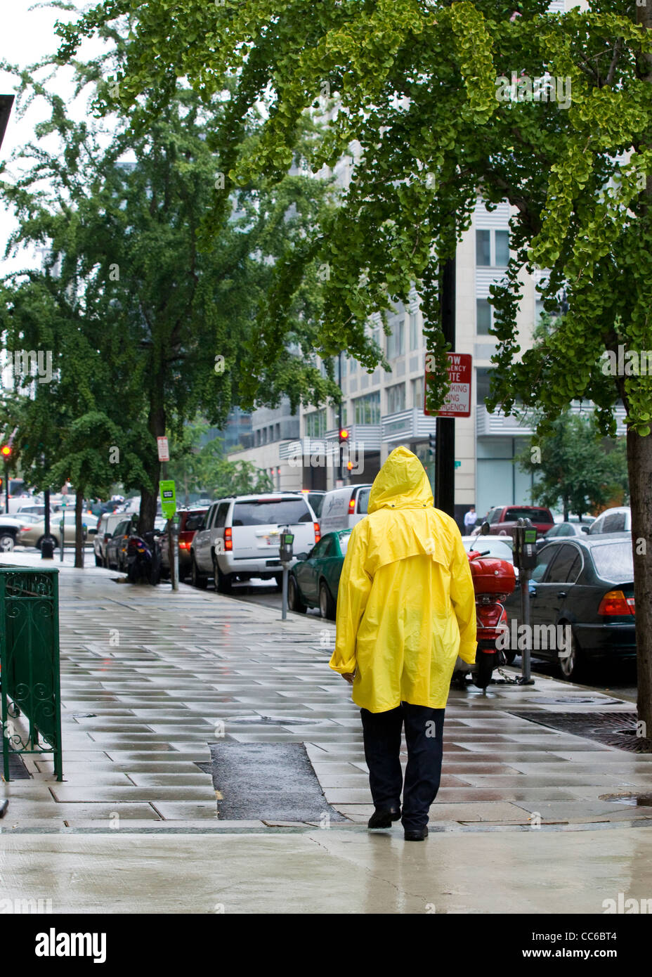 Ein Mann, der im Regen läuft und einen gelben Regenmantel trägt - USA Stockfoto