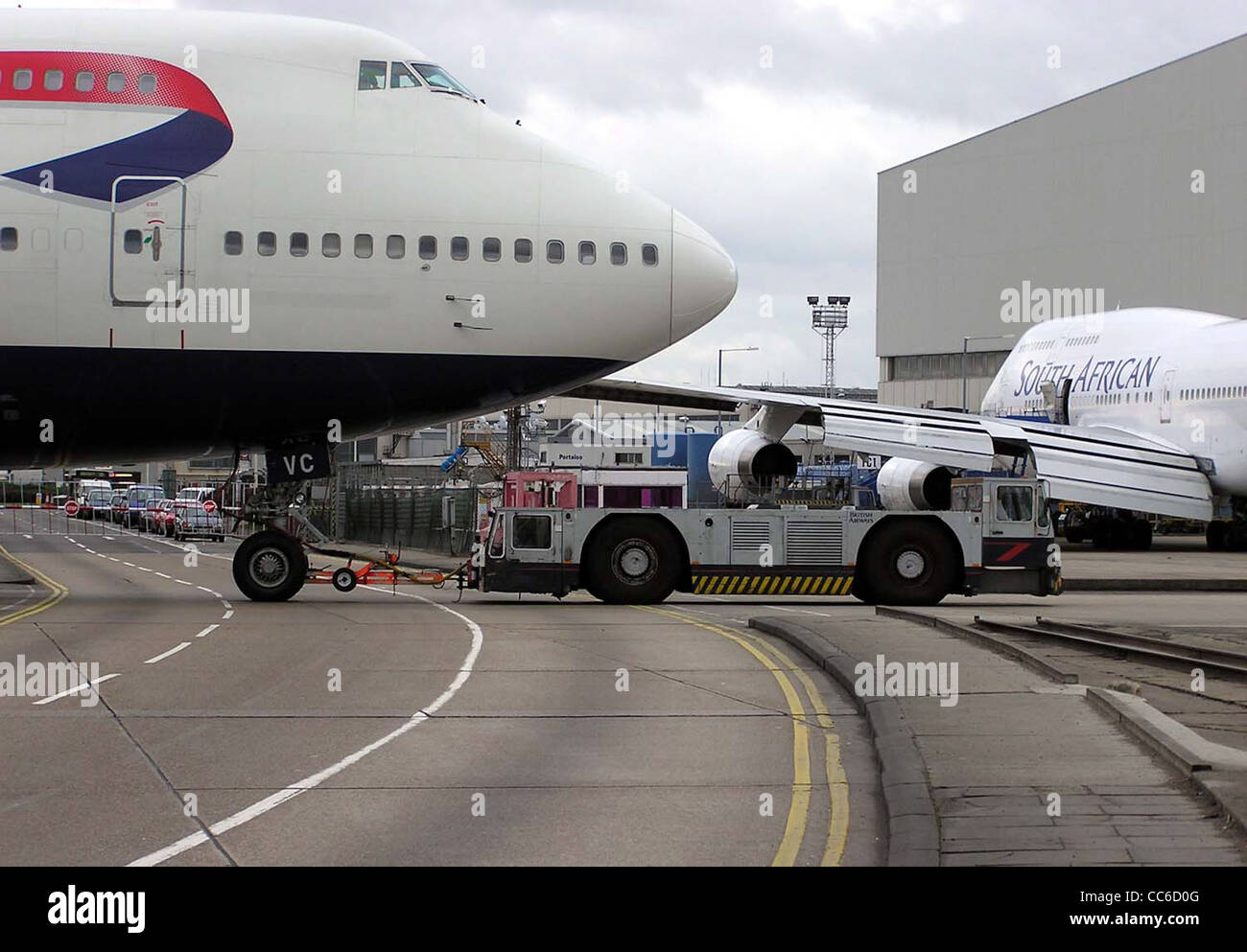 Eine British Airways Boeing 747-400 (G-CIVC) wird am Flughafen London Heathrow von einem Schlepper gezogen. Die Boeing 747-400 ist ein Großraumflugzeug für den internationalen Flugverkehr. Stockfoto