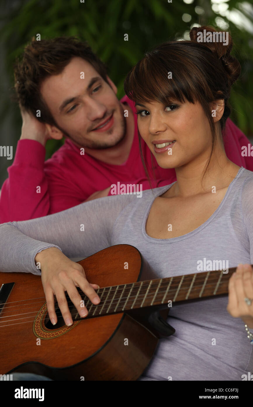 Lächelnde junge und Mädchen spielt Gitarre Stockfoto