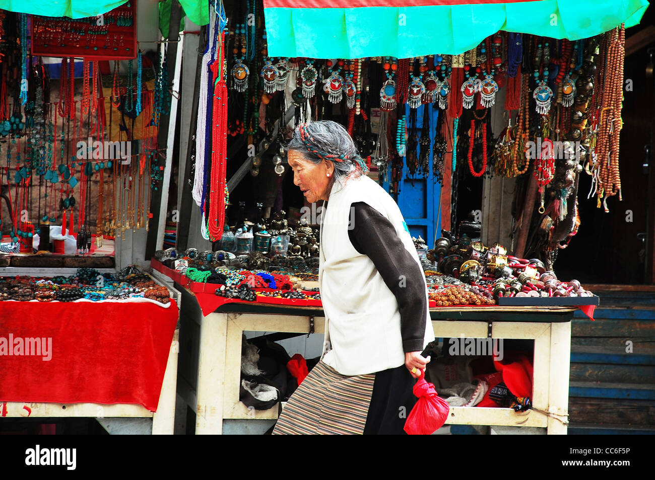 Tibetische Seniorin vorbei an Souvenir-Stände, Barkhor Street, Lhasa, Tibet, China Stockfoto