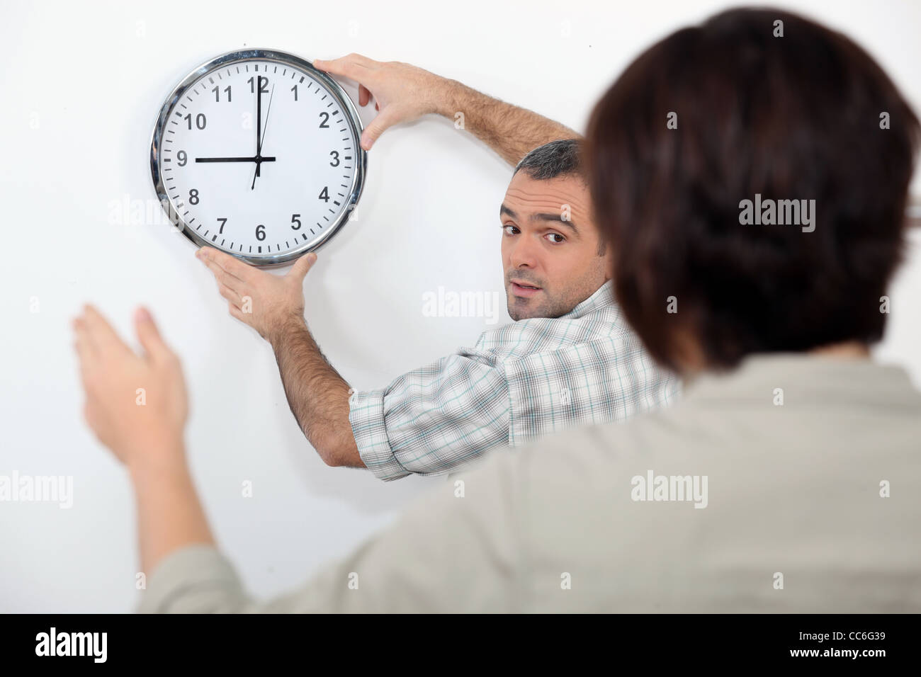 Paar Begradigung einer krummen Uhr Stockfoto