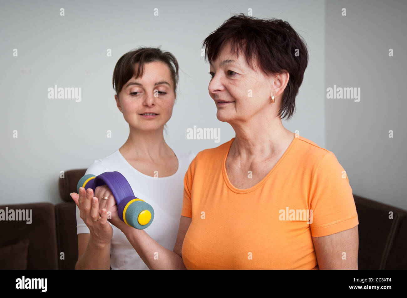 Trainer unterstützen ältere Frau, die das Training mit Hanteln Stockfoto