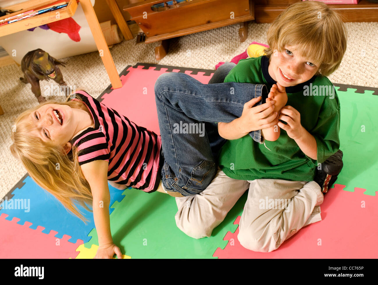 Zwillinge, Ringen und kitzeln in ihrem Spielzimmer Stockfoto