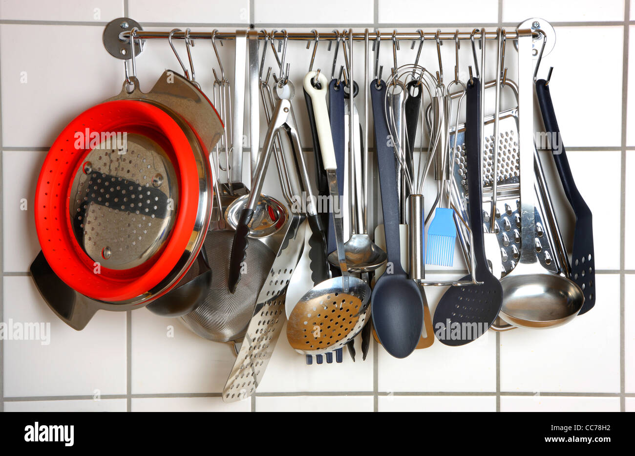 Diverse Küchenutensilien, Küchengeräte, hängen an einem Küche Wand Rack. Stockfoto