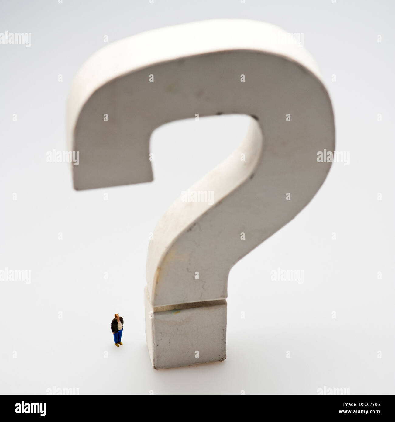 die große Frage - kleine Figur dominiert von einem großen großen riesigen monumentalen Fragezeichen Stockfoto