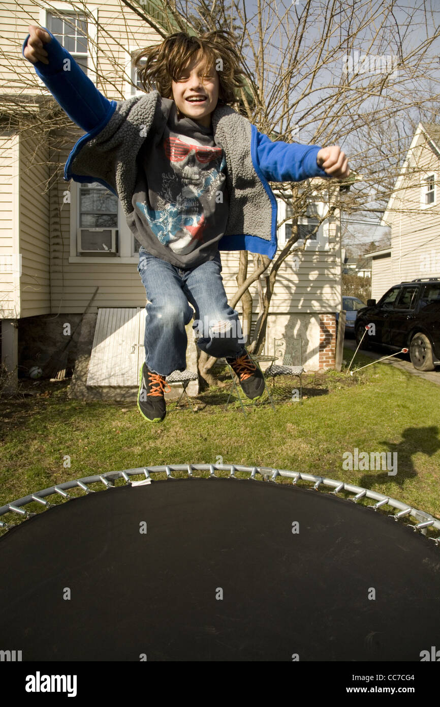 Sieben Jahre alter Junge hat Spaß trainieren auf einem Trampolin in seinem Hinterhof in Darien, Connecticut. Stockfoto