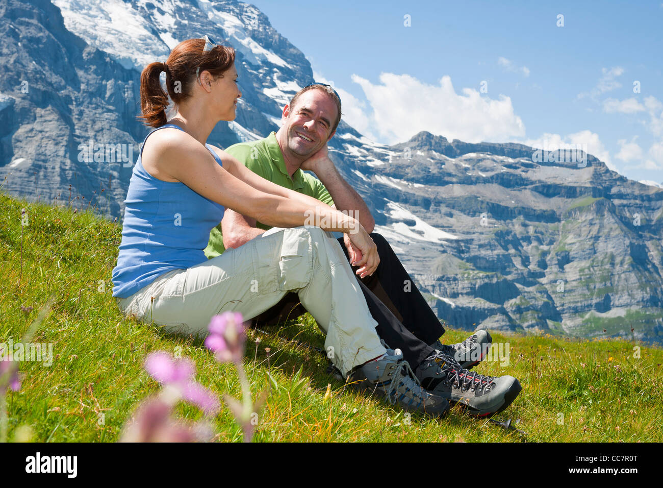 Paar sitzt am Berghang, Berner Oberland, Schweiz Stockfoto