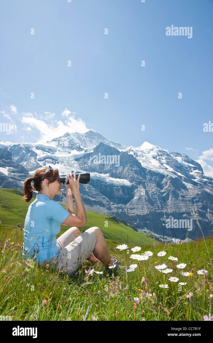 Frau sitzt auf der Bergseite mit Fernglas, Berner Oberland, Schweiz  Stockfotografie - Alamy