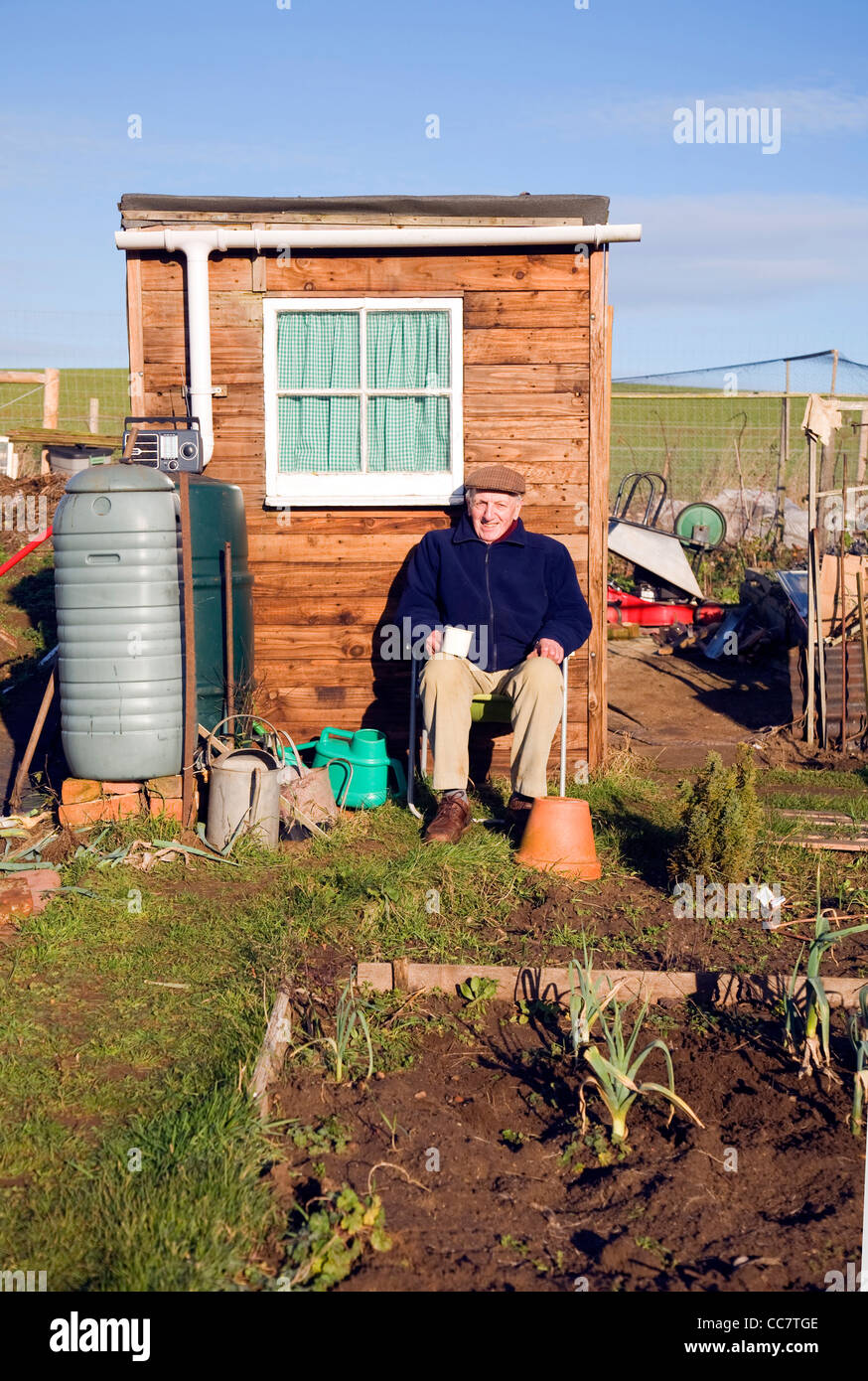 Ältere Mann sitzt durch Schuppen Schrebergarten Suffolk England UK Stockfoto