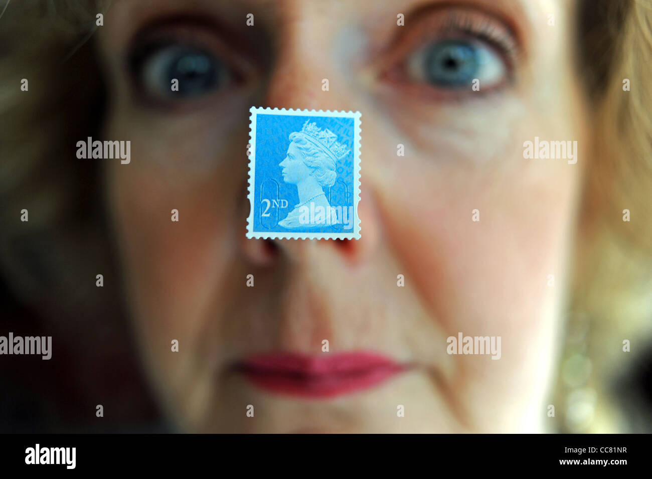 Applying Frau nahe Gesicht mit einem britischen zweiten 2. Klasse Briefmarke klebte an Nase Modell Stockfoto