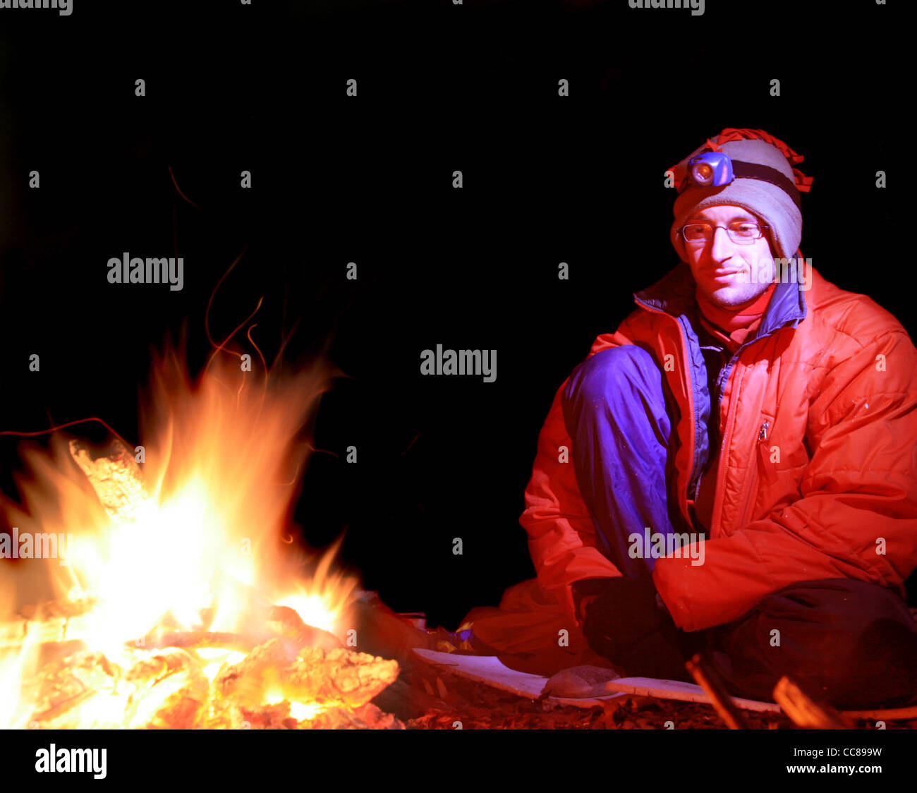 Langzeitbelichtung eines Mannes in kaltem Wetter Kleidung sitzen am Lagerfeuer Stockfoto