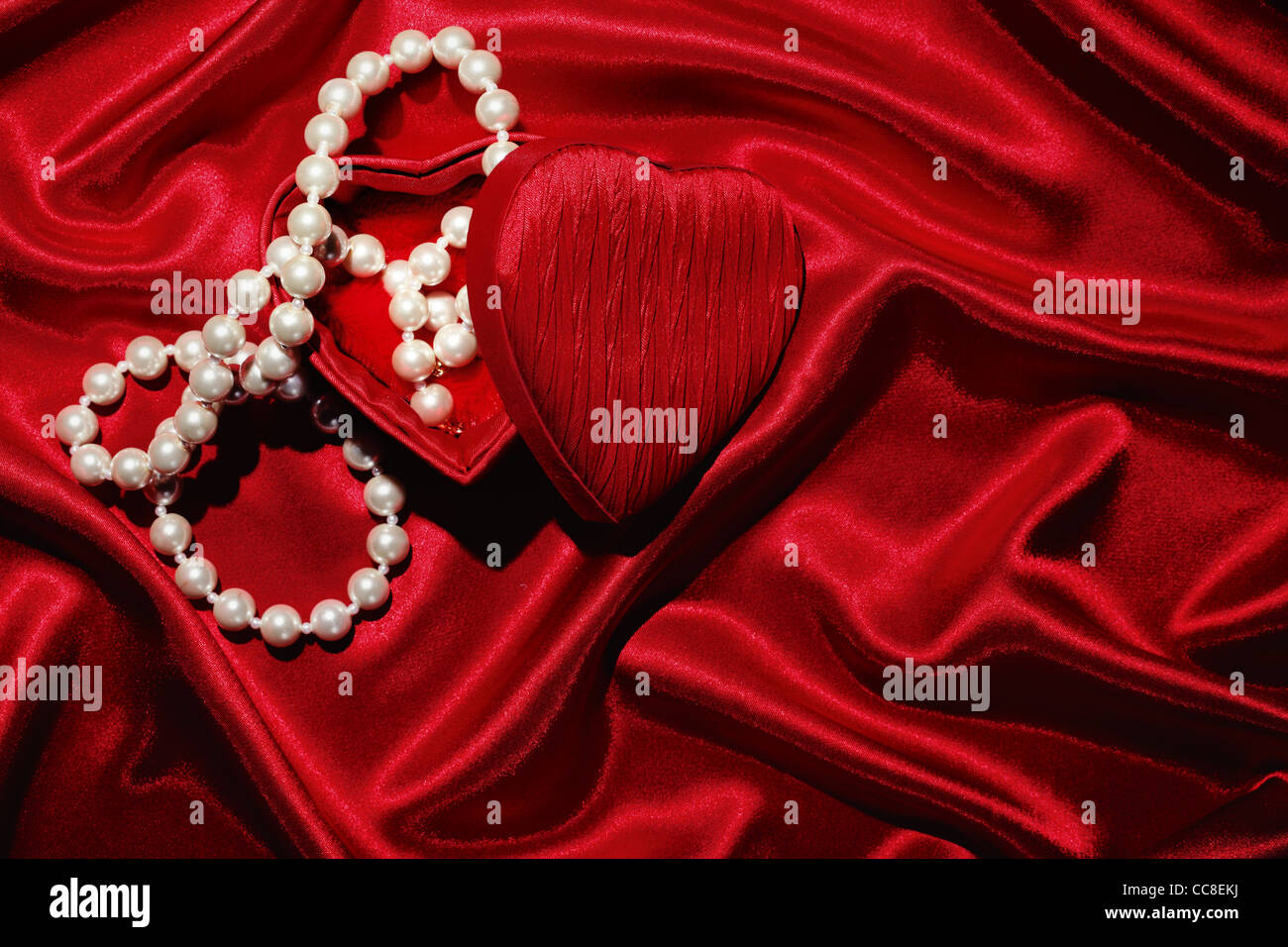 Rotes Herz-Form-Box mit Halskette auf Seide Hintergrund Stockfoto