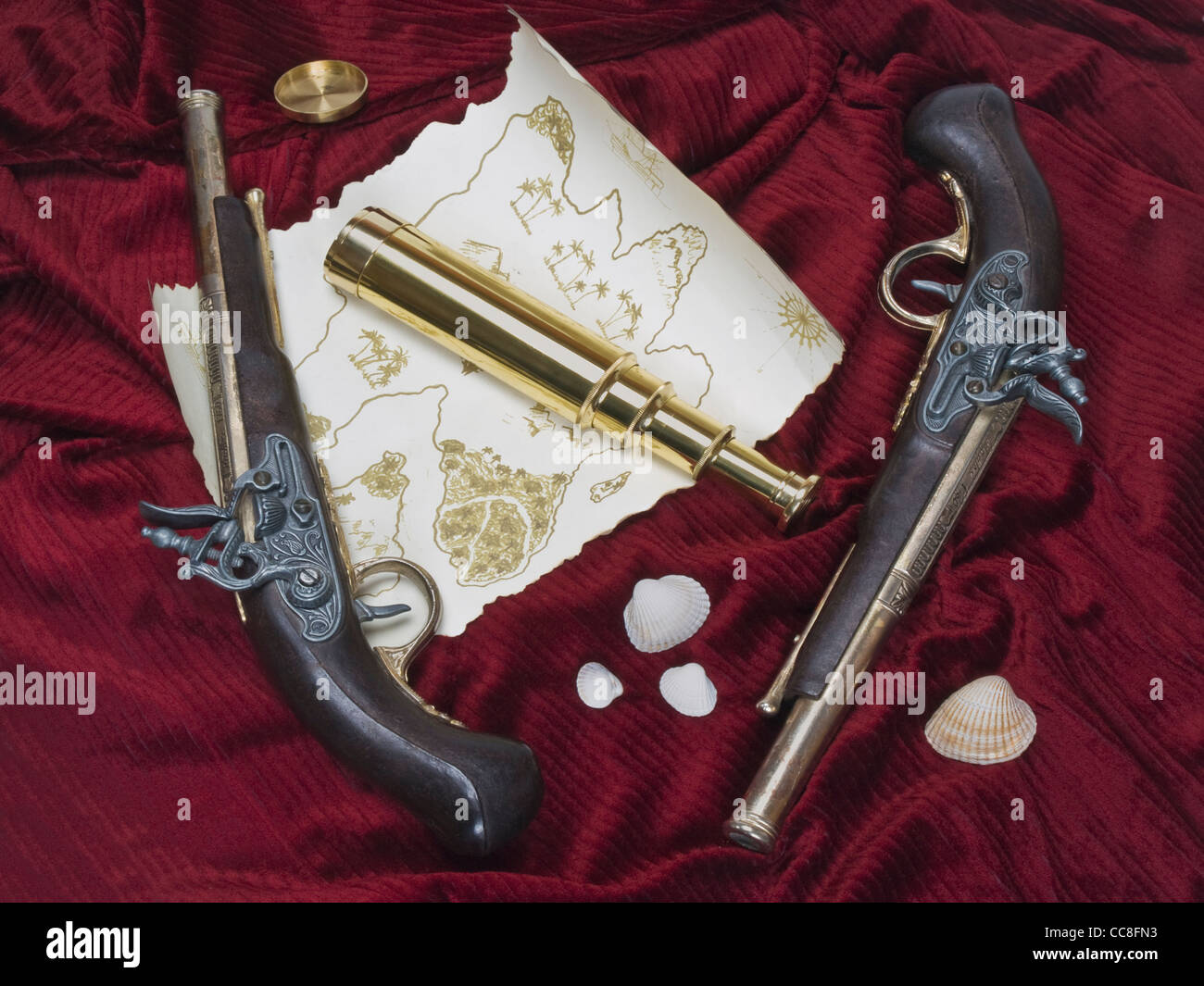 ein Monokular Teleskop auf einer Schatzkarte in der Nähe befinden sich zwei alte Pistolen und einige Shell Muscheln Stockfoto