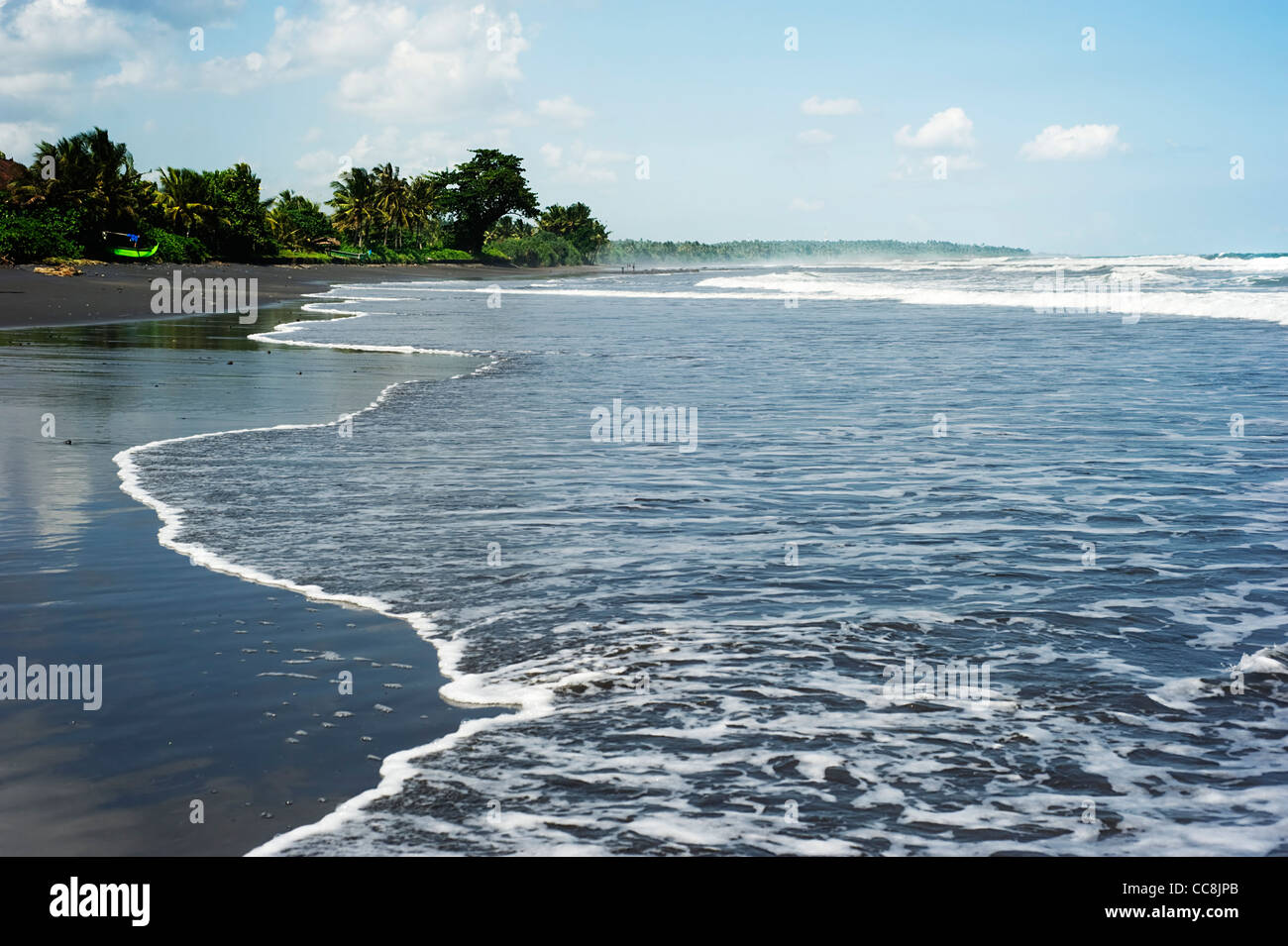 Strom aus dem Meer am schwarzen Sandstrand. Bali, Indonesien Stockfoto