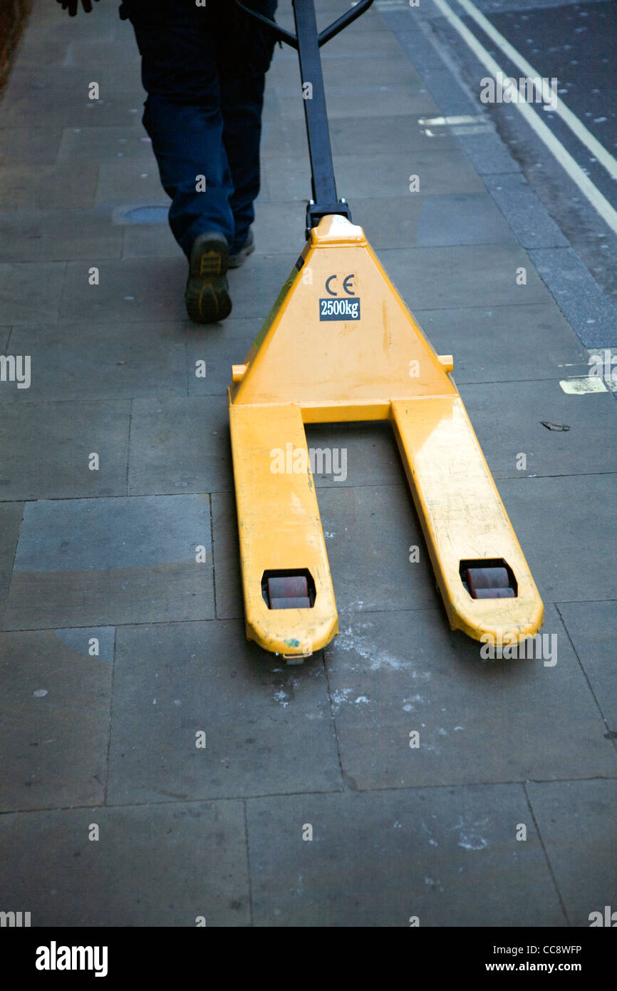 Man zieht gelbe Gabel Lift Paletten LKW Pflaster Stockfoto