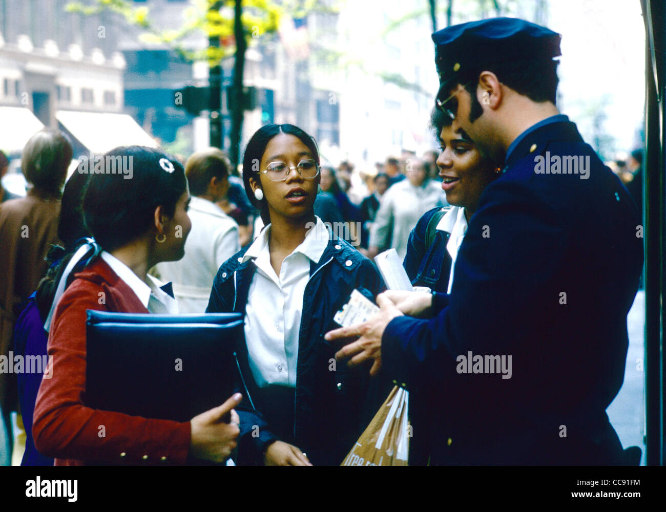 Junge Frauen in eine freundschaftliche Begegnung mit einem New York Polizei Mann auf der Fifth Avenue Stockfoto